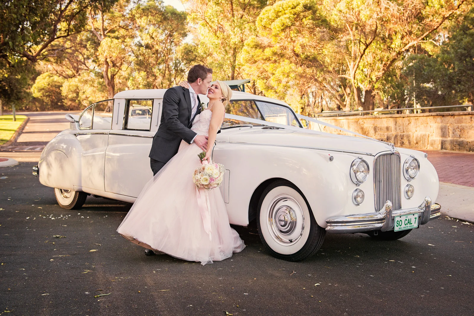 Bride and Groom embracing in front of white convertible Jag at Neil Hawkins Park.