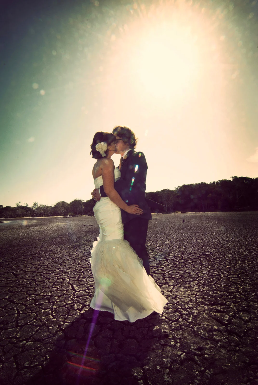 Couple kiss and embrace in the midday sun on dried clay bed at Esperance Wetlands.