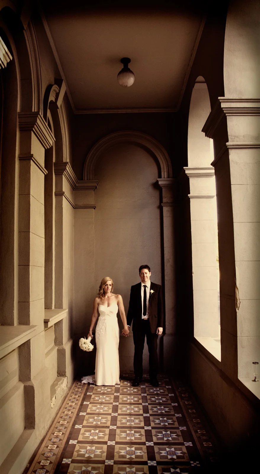 couple standing apart holding hands in art deco building, Fremantle