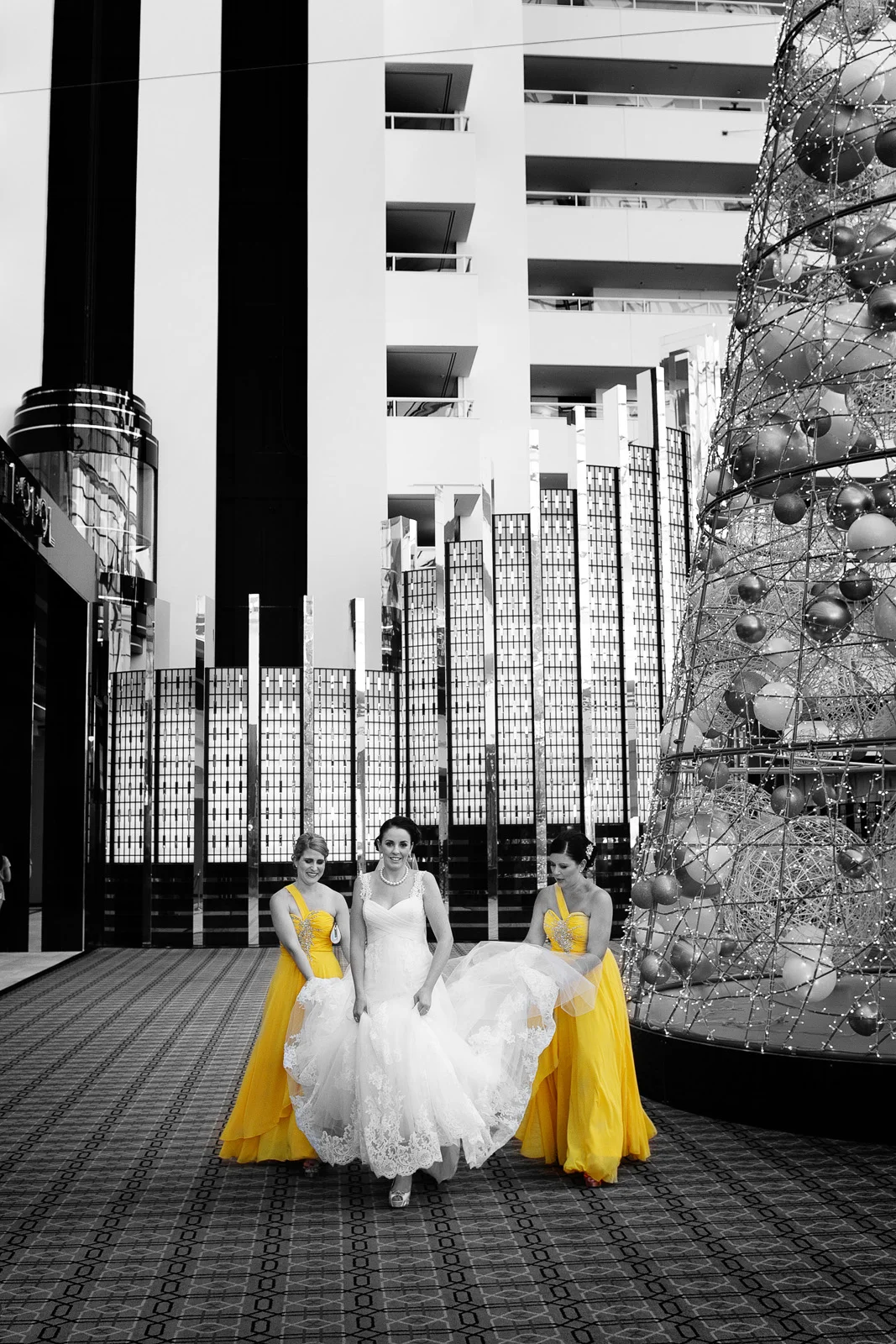 Bride with bridesmaids in yellow helping to carry dress at the Crown hotel. Perth