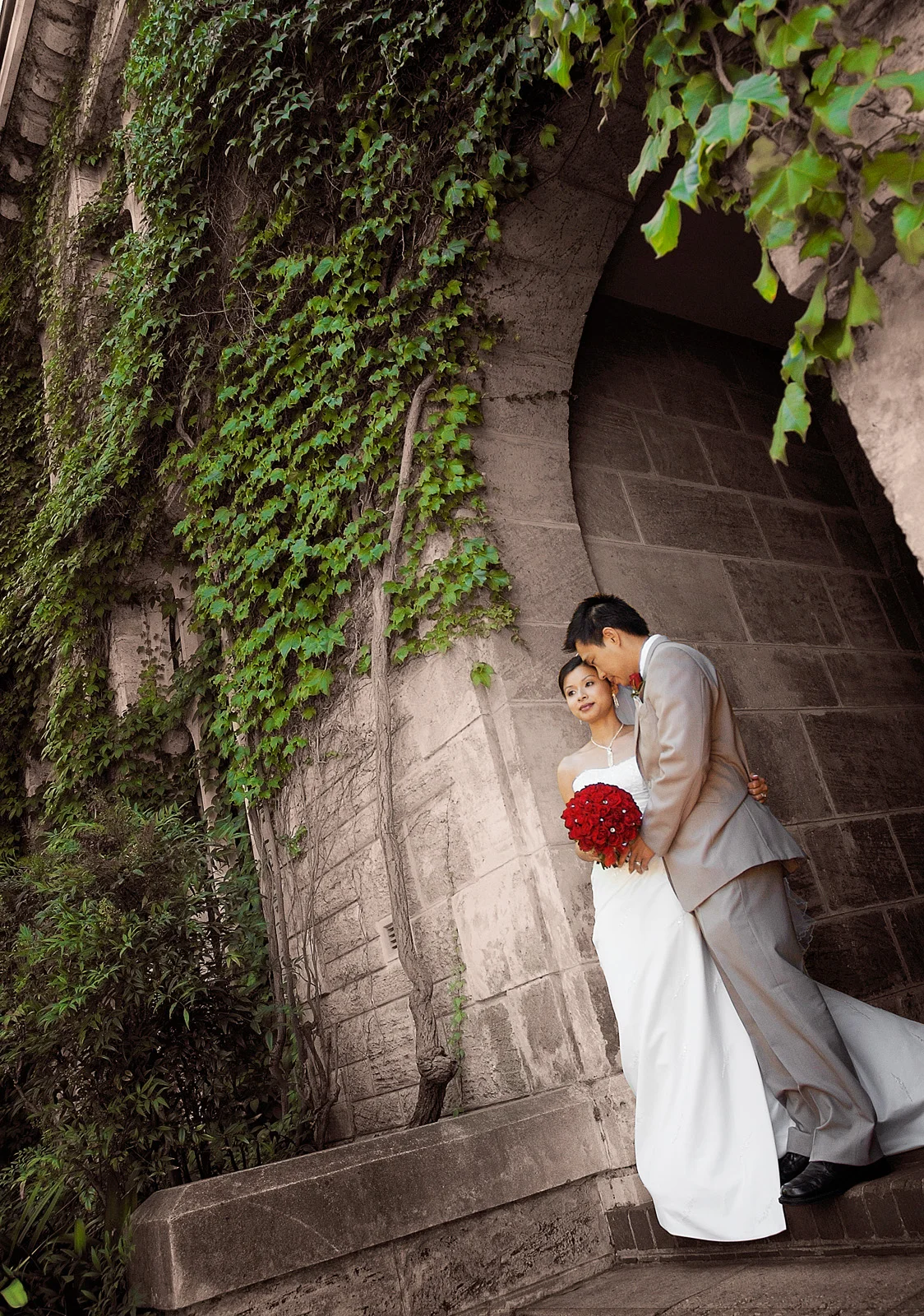 couple standing under Ivy covered archway at UWA. Nedlands