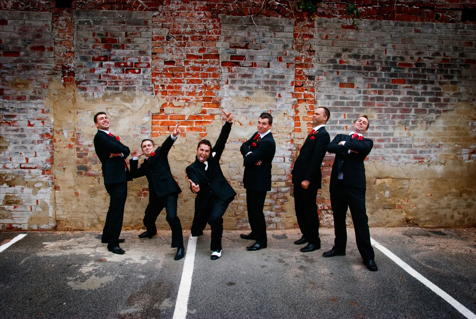 groomsmen fun pose in front of rustic brick wall. Fremantle