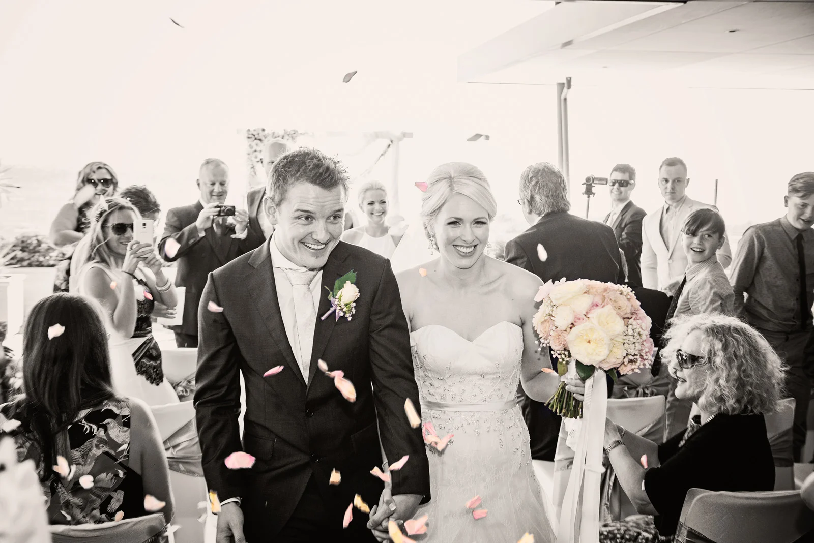 Guests congratulate couple as they walk down the aisle by throwing petals