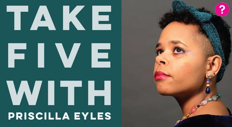 Take Five With Priscilla Eyles - pictured is a closeup of Priscilla staring into the distance, wearing a sparkly green headband, multicoloured gemstone earrings and a necklace