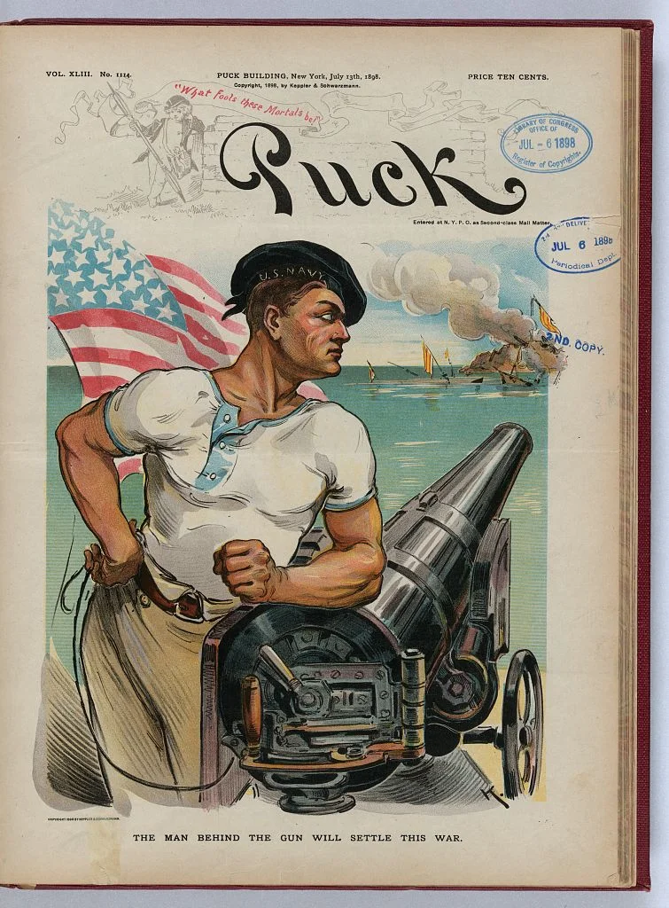 Cover of Puck, July 13, 1898. An American sailor wearing a cap labeled "U.S. Navy", leaning on a ship cannon, with an American flag behind his right shoulder and the ruins of the Spanish fleet in the background. Library of Congress Prints and Photographs Division