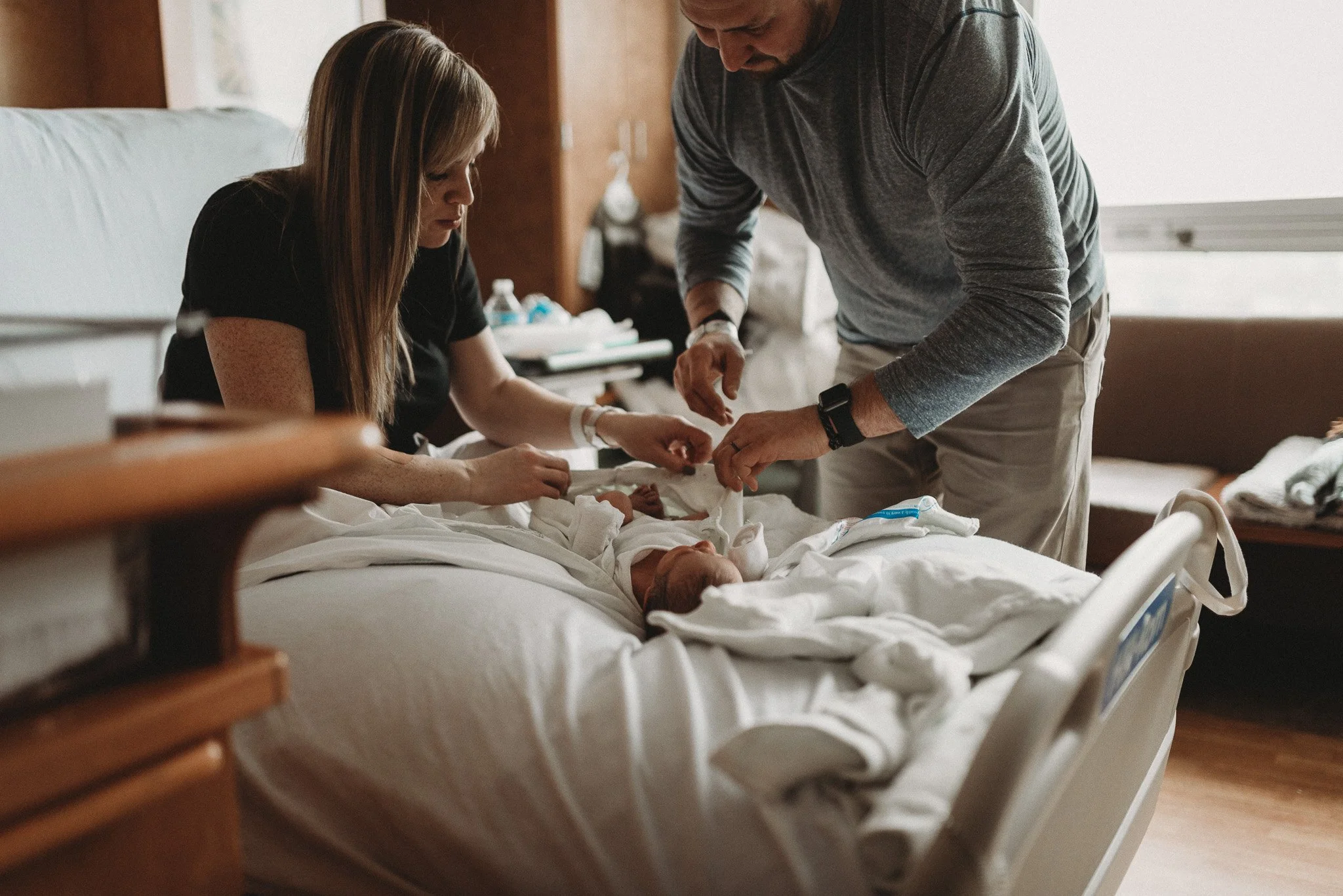 Mom and Dad wrapping newborn baby in a blanket during Fresh 48 session