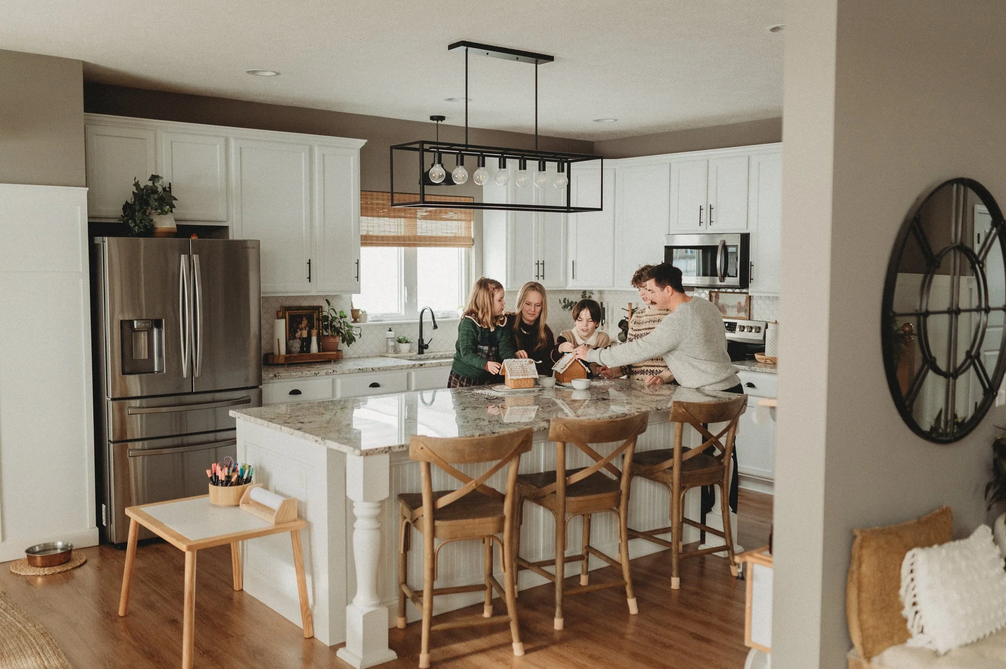 A family decorating gingerbread houses in their kitchen during a documentary family photography session
