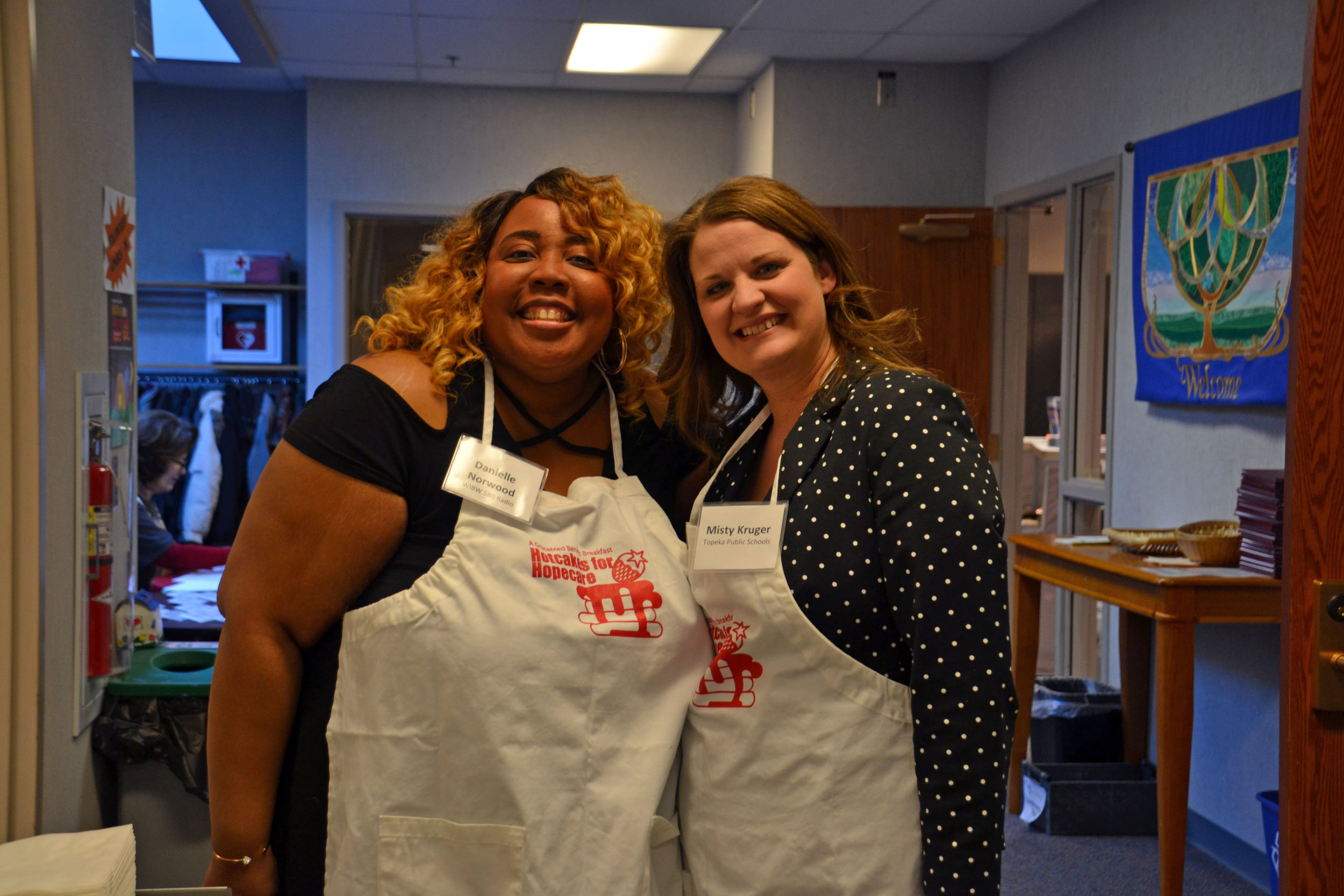 Danielle Norwood from WIBW and Misty Kruger from Topeka Public Schools take a break from serving
