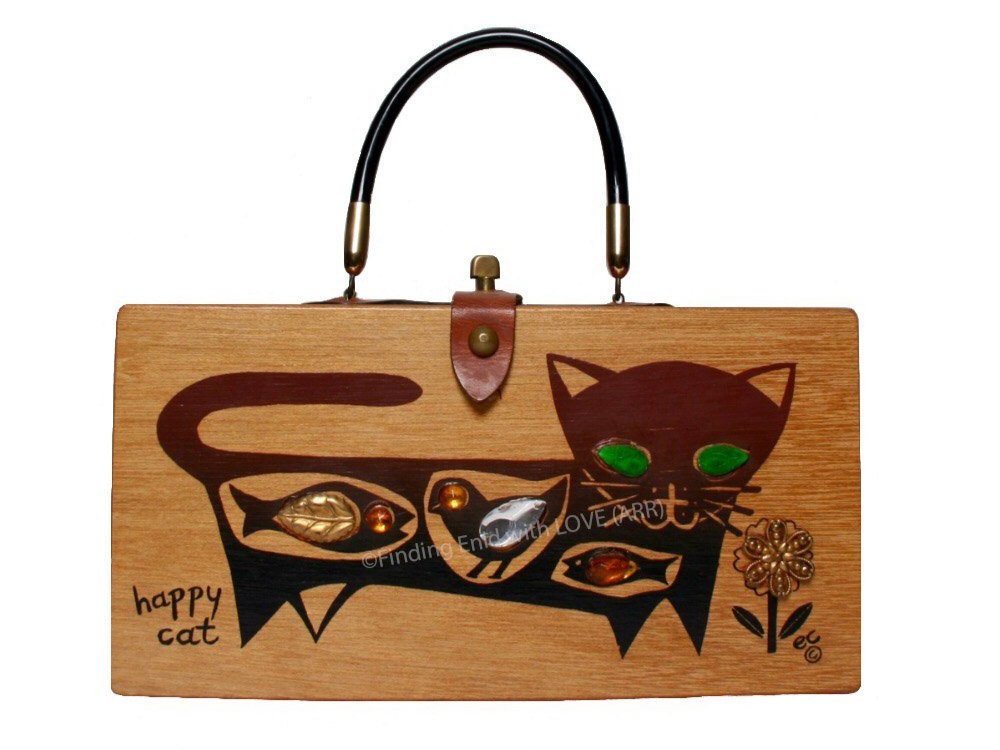  The mid-century Collins of Texas box bag was made of solid wood with hand-wrought brass,  hand-stained leather trim and a rigid vinyl handle. Designs were at first hand painted onto the fronts and/or tops, but later screenprinted. Jewels were glued 