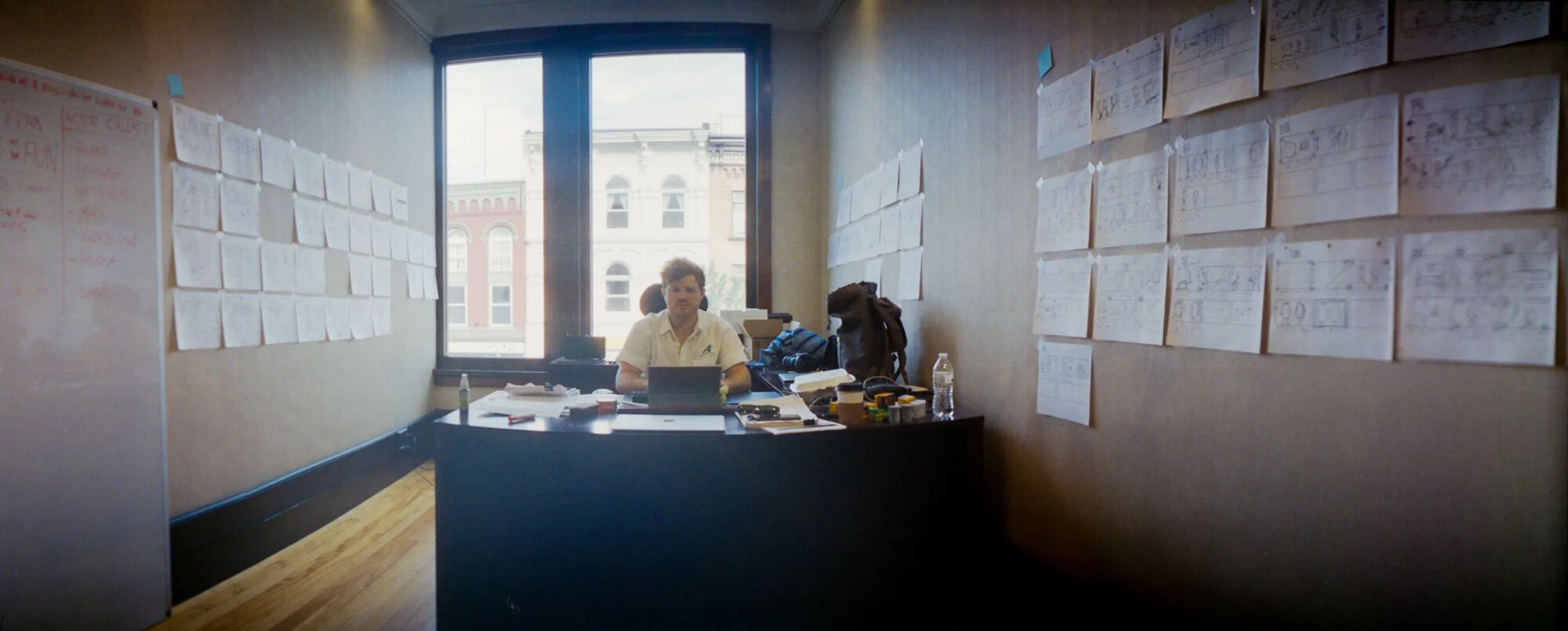 Drew in office with his walls of chicken scratch storyboards