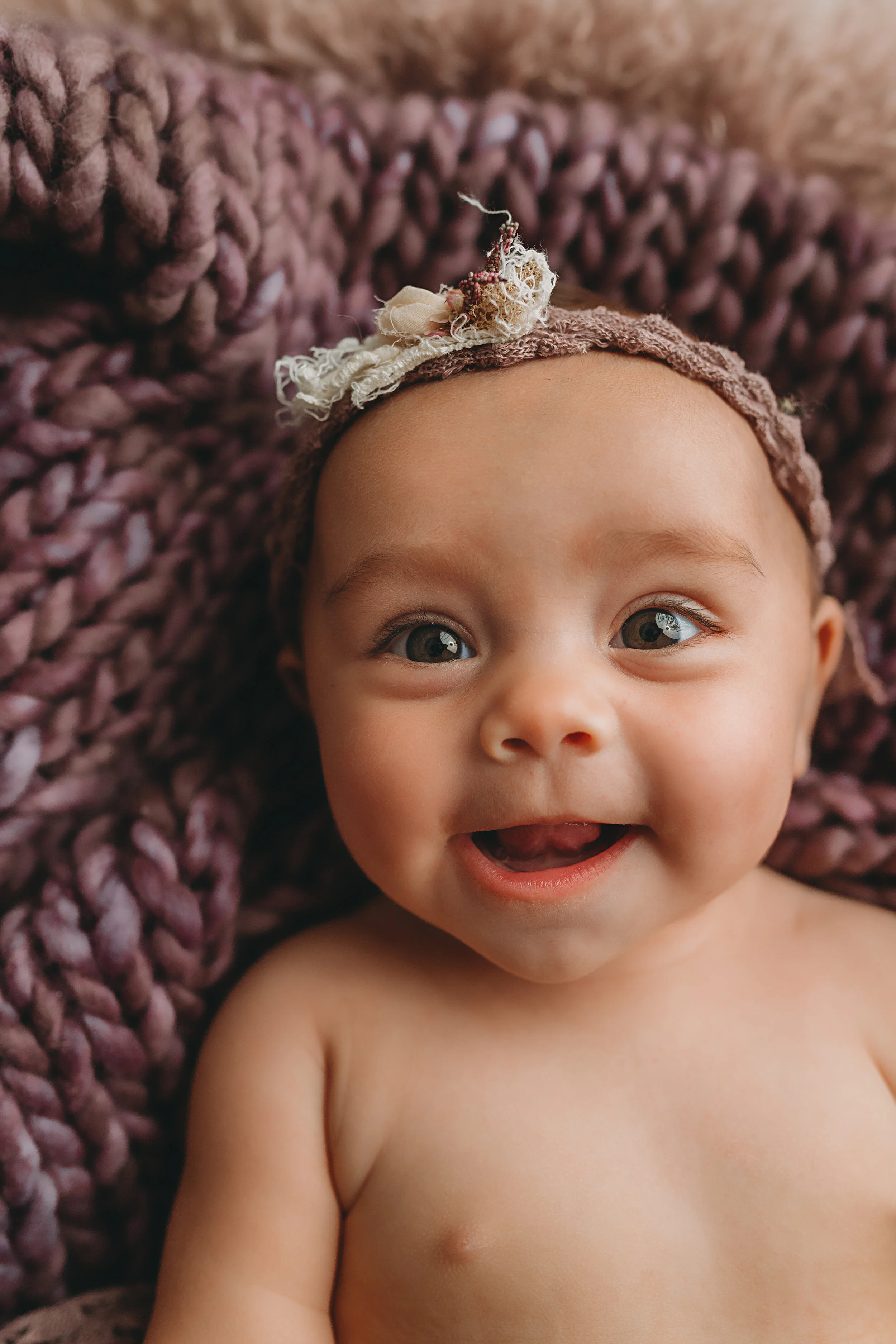 Baby girl on purple and floral layer smiling at camera during milestone session Chasing Sammi Photography studio in Springfield Missouri