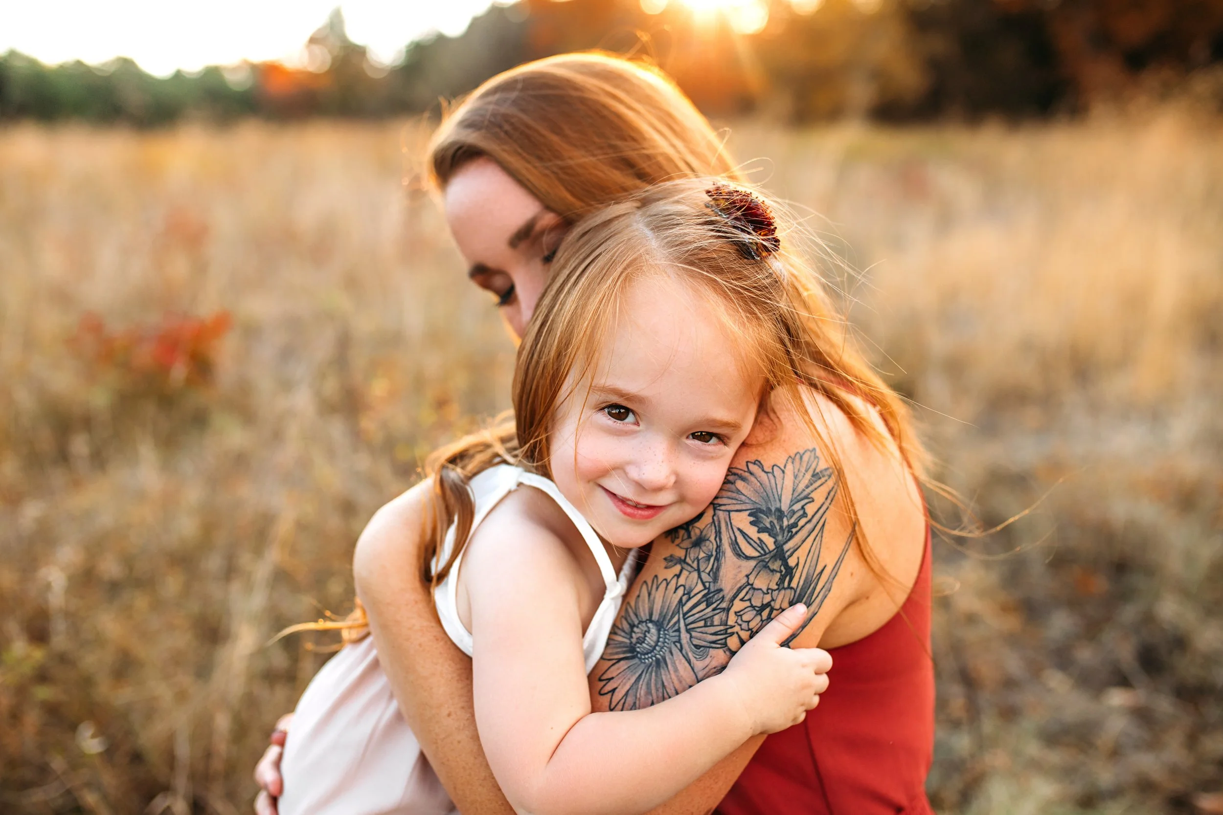 Daughter embracing her mother and smiling at the camera during a fall family session in Springfield Missouri