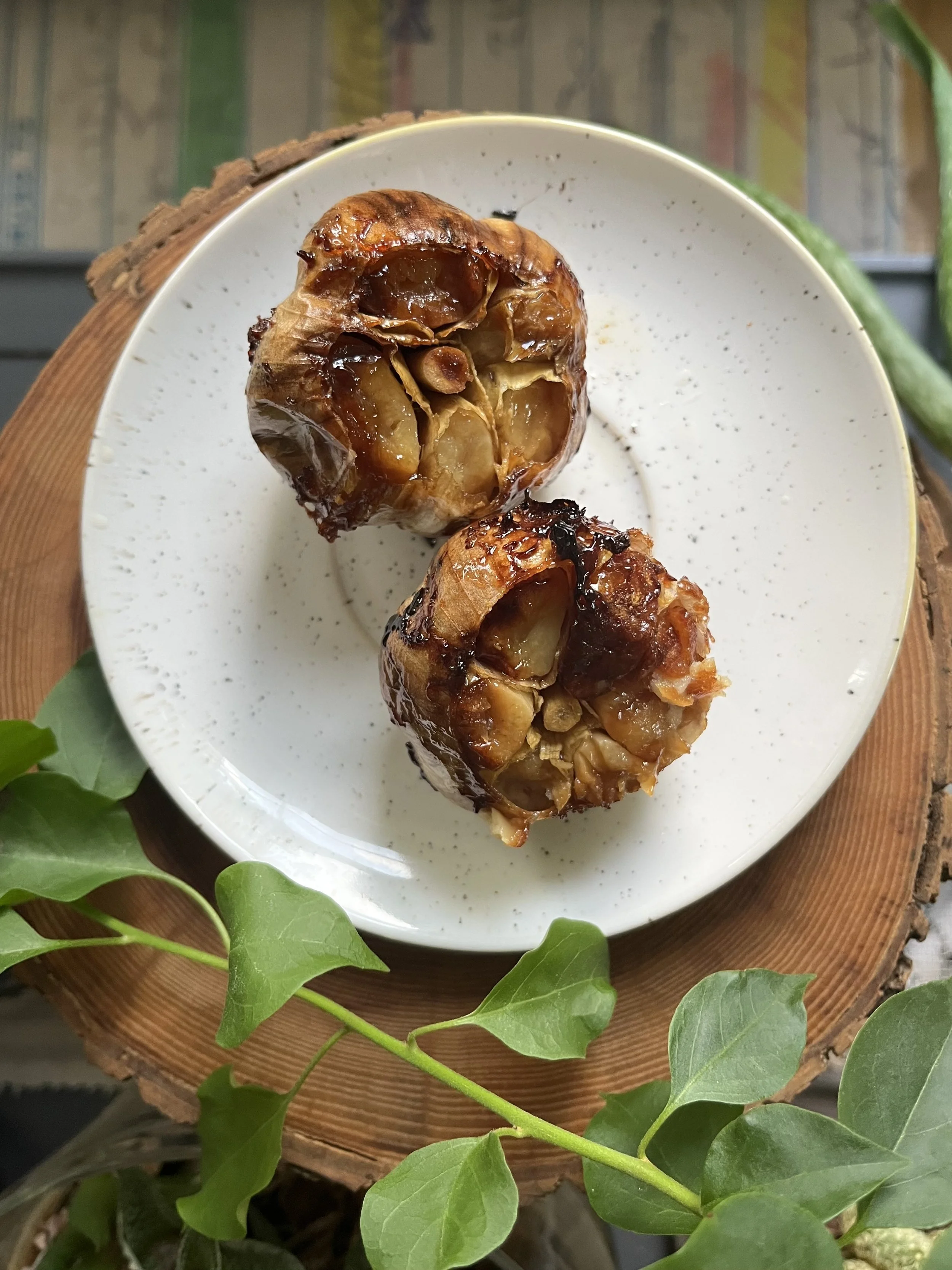 Roasted garlic halves sitting on a plate. Golden brown and caramelized.