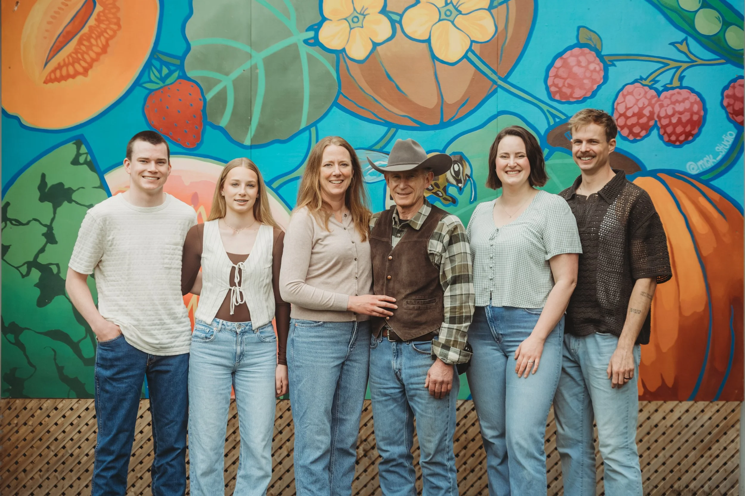 Family of 6 standing in front of a fruit and vegetable mural