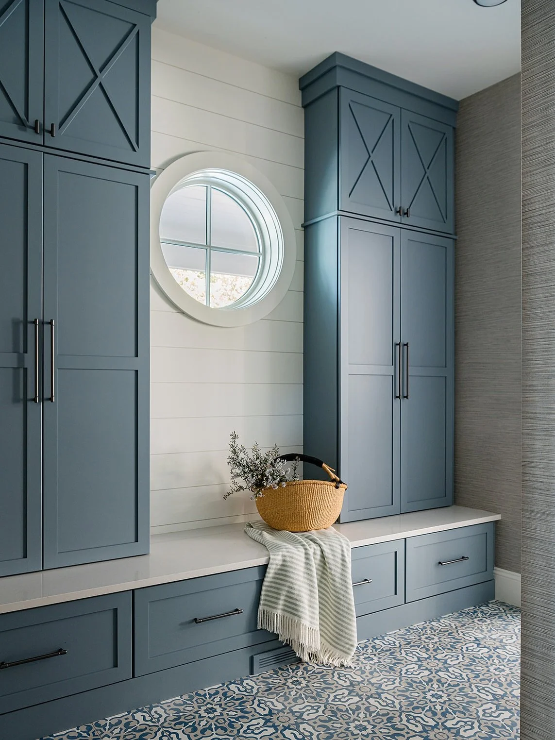 Tucked just off the entry at Lakeshore Lanes, the complementing mudroom and powder room balance function and beauty with ease. The coastal palette sets a relaxed tone, while warm metal accents, concrete floor tiles, and patterned wall covering add ri