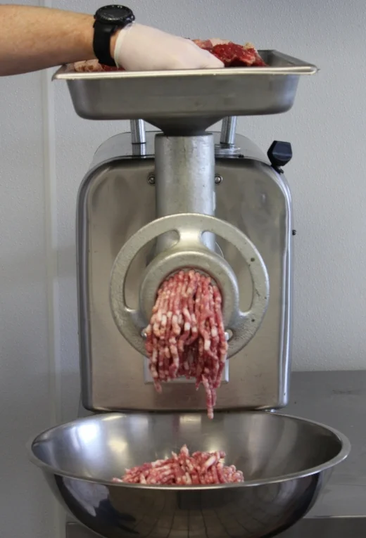 Grinding: Once your chilled grinder attachment is setup, per the manufacturer's instruction, you will feed the seasoned meat through. As a general rule, we send the meat through the grinder twice. Once with the large die and a second time with the smaller die, although this can vary widely from recipe to recipe as there are many different size dies used for different results. Ensure that the meat has been removed of any sinew, which can get tangled in the blade, creating the "smear" effect. Also similar to "breaking" the sausage mixture. A well executed grind will extrude cleanly out of the die in a uniform texture, where the meat and fat are still distinguishable from each other. In order to keep the mixture below 40 degrees, grind into a bowl over ice.