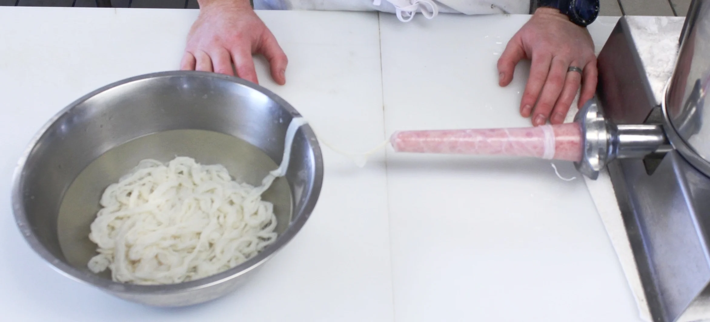 Stuffing: Most sausage recipes will call for a natural casing. These are the lining of intestine from a sheep, hog or cow and come in a variety of sizes and lengths. When using natural casings you will need to soak them in tepid water for at least 30 minutes. Then, rinse them by holding one open end up to a running faucet, allowing the water to pass through the casing and out the other end. Reserve in a bowl with water until ready to feed onto stuffer tube. When stuffing the casing, pack the sausage mixture before feeding into stuffer to remove any air pockets. Once the mixture and casings are ready, slowly and uniformly feeding the meat through the stuffer tube while holding the casings with one hand. By dictating how fast the casings are released you will be able to control how tightly filled the sausage will be. Aiming for the casings to be three-quarters full, you will have uniformly shaped links, with out causing blow-outs during linking.