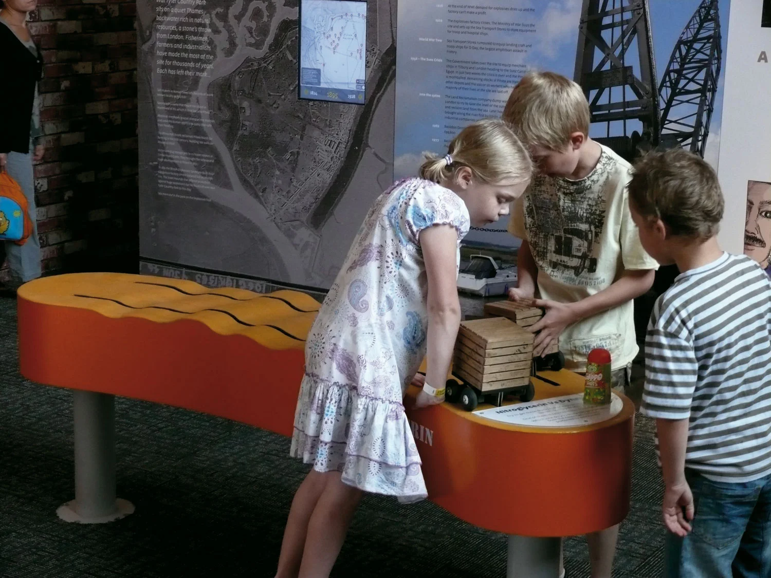 Children move two trucks across a bumpy terrain, learning that nitroglycerin blows up much more readily than dynamite