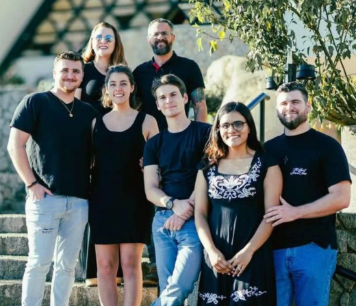 Missionaries Hassan and Stacy Villegas and their three sons and two daughter in laws standing on an outdoor staircase and posing and smiling at the camera