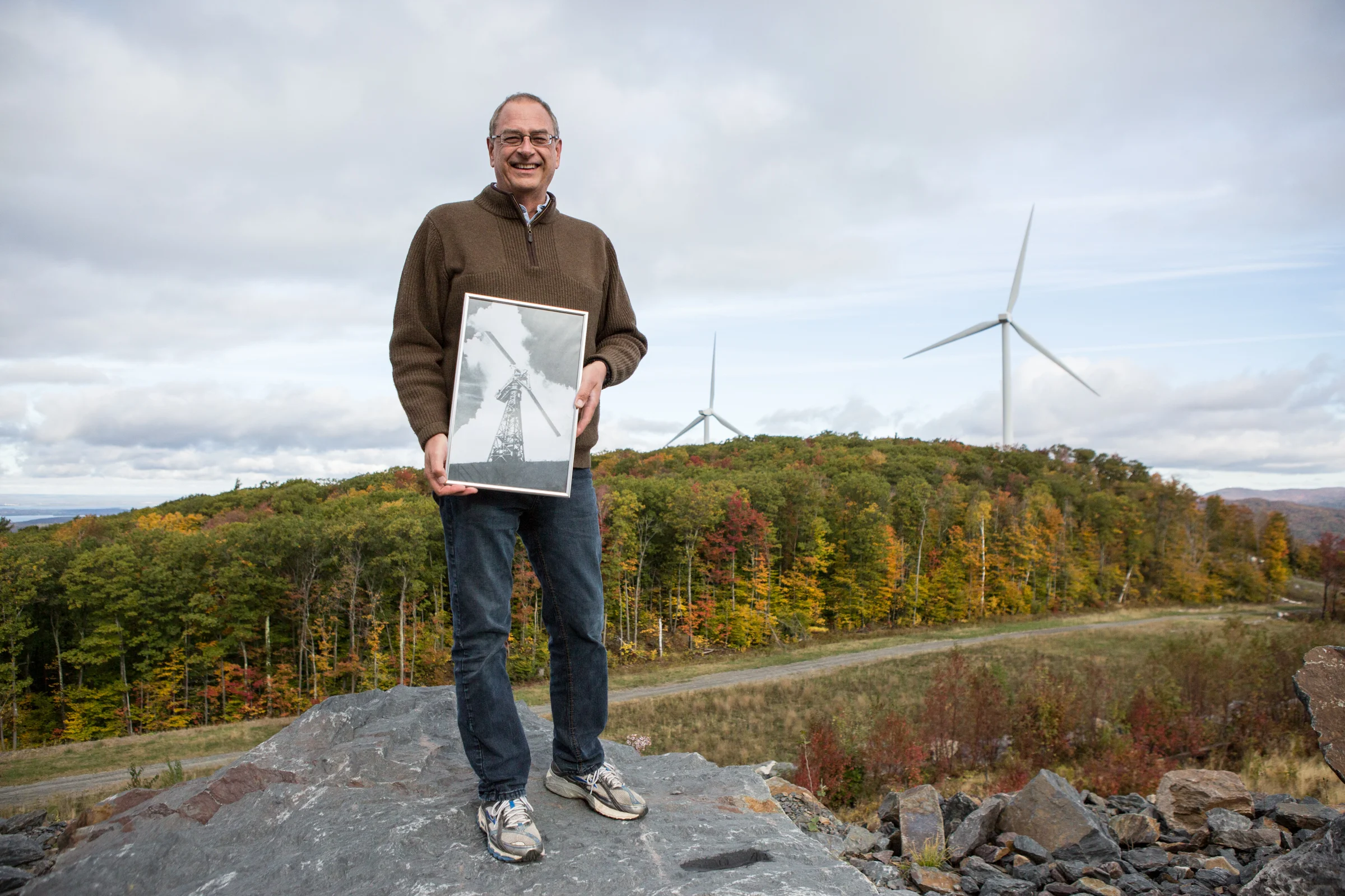 David Blittersdorf at the 10-megawatt Georgia Mountain Community Wind farm constructed in 2012 on the Milton-Georgia town border, holding an archival photo of the Smith- Putnam wind turbine–the world’s first utility-connected wind turbine, which was built in 1941 atop Grandpa’s Knob in Castleton, VT. Photo by Ned Castle.