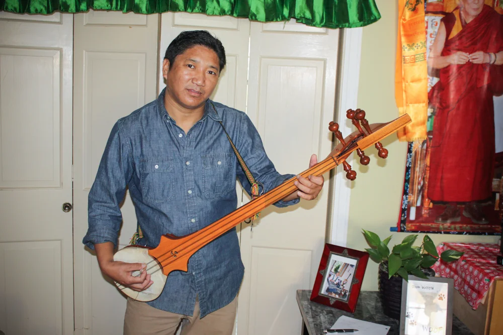 Migmar Tsering posing with his Dramyin - a traditional Tibetian instrument he has been playing since he was a child. Migmar has lived in Vermont since 2011 and is the President of the Tibetan Association of Vermont.