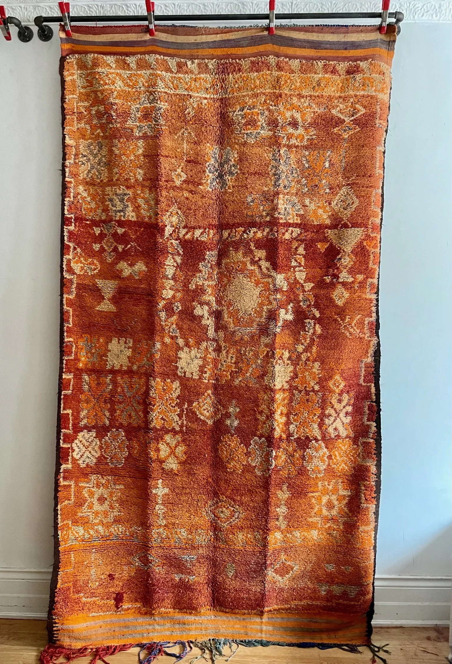 orange vintage moroccan wool rug with pale blue and cream motifs and cream greek key borders