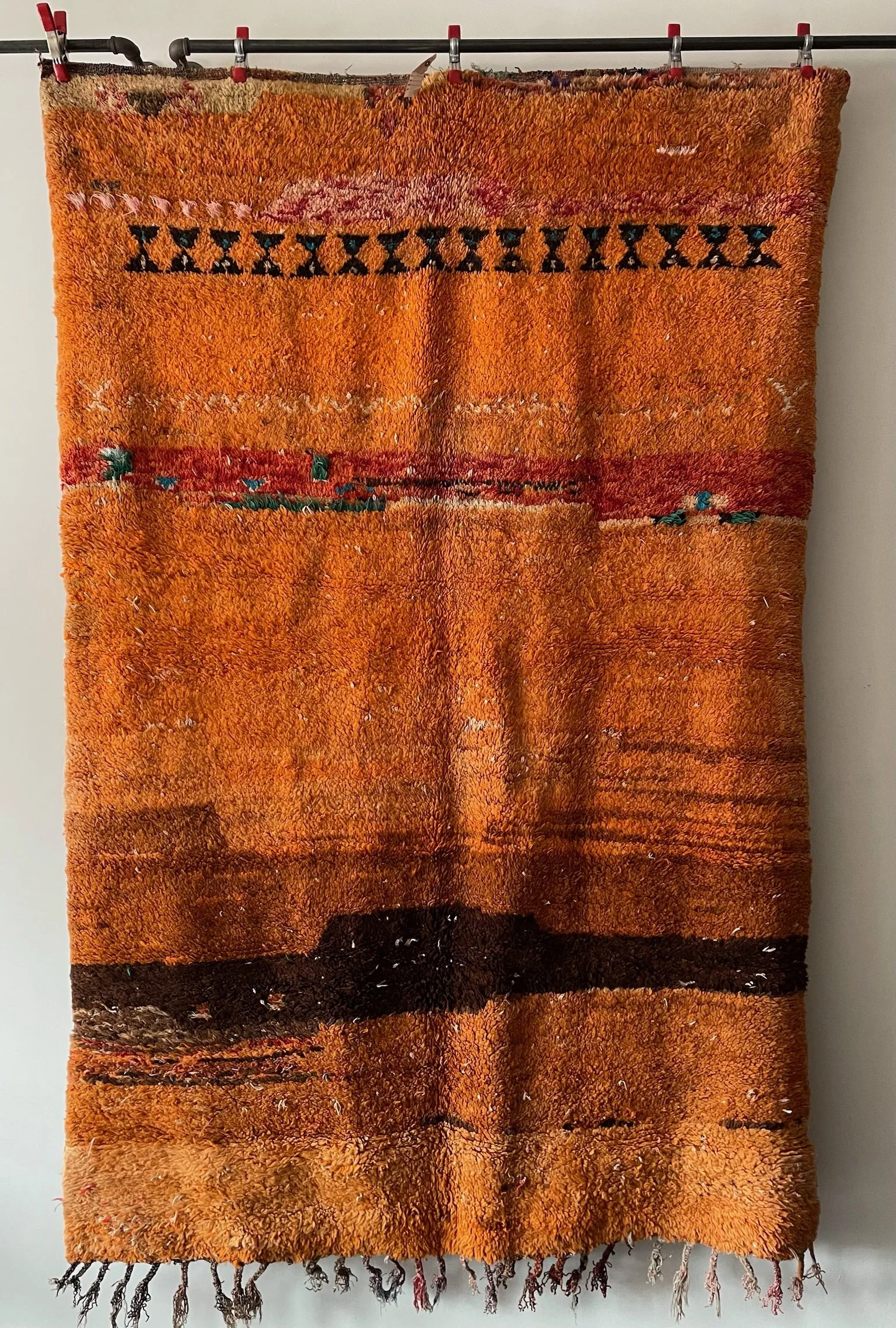 an orange tribal vintage moroccan rug with a minimalist design. bands of brown and red throughout