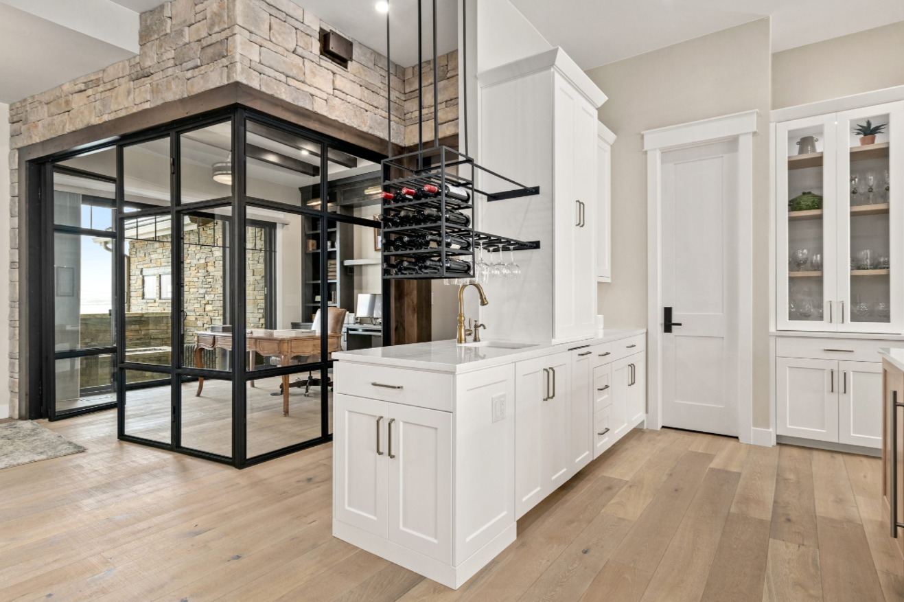 White custom cabinetry beside a glass-walled room and beverage storage