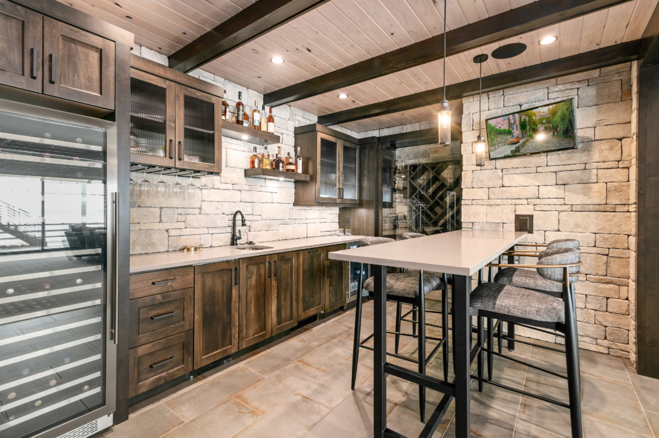 Dark wood bar cabinetry with glass fronts and stone walls