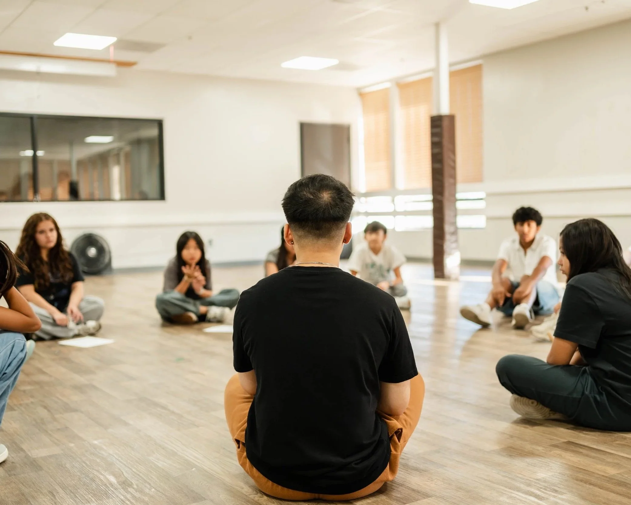 Dance team members sitting together during a team discussion at re.DEFINE Dance Studio in Hayward, California.