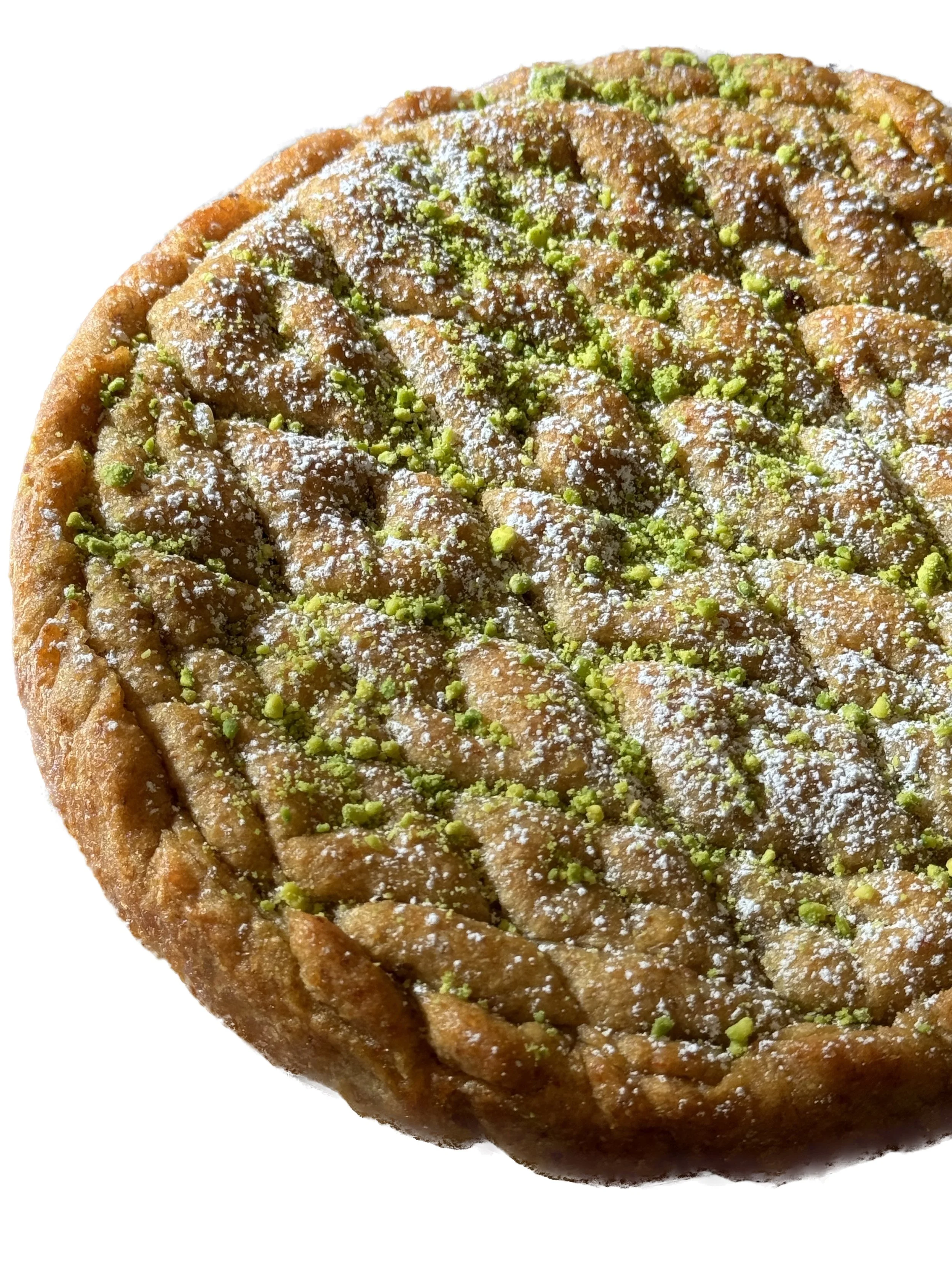 Close-up of a round pistachio pastry dusted with powdered sugar.