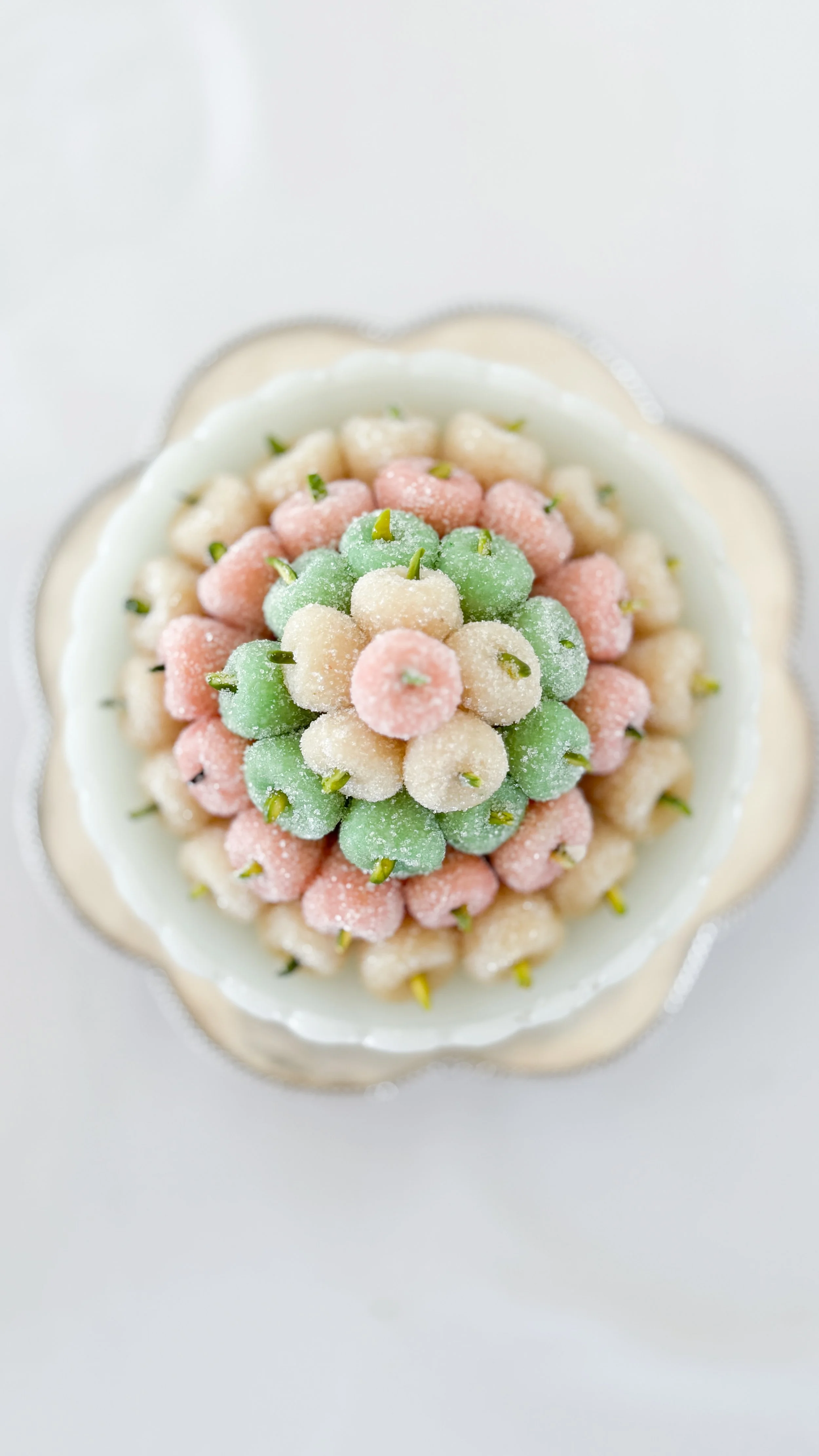 Colorful toots / Iranian Marzipan pastel green, pink, and white arranged in a flower shape, sitting in a white bowl.