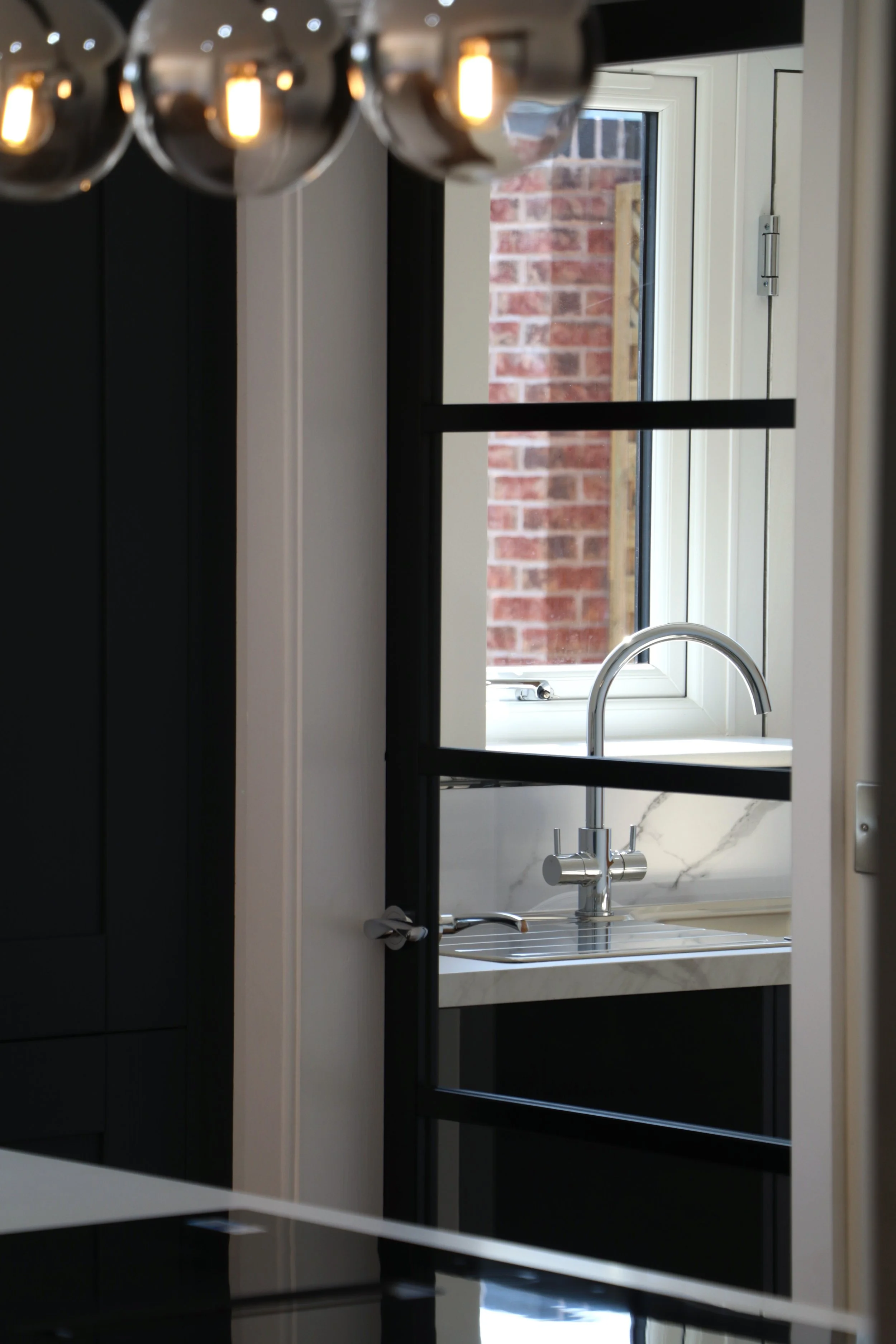  Striking Crittall-style doors and screens provide a sharp contrast to the soft quartz stone worktops and bespoke kitchen cabinetry. 