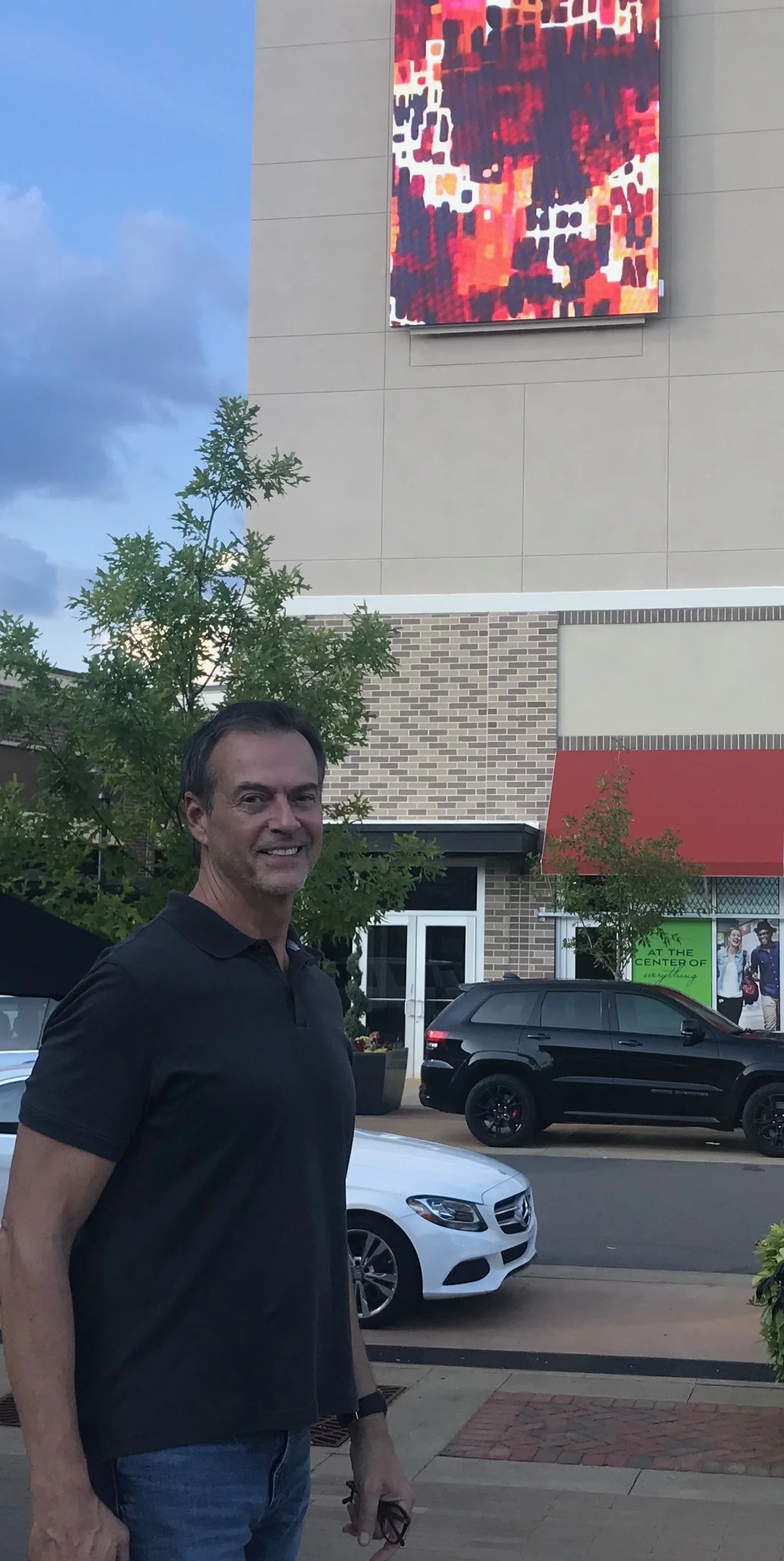 Robert standing beneath the digital billboard at Waverly South Charlotte, featuring images of several of his paintings. Wendy Hickey of ArtPop Street Gallery teamed up with Dennis Boyle and Katie McLean of Awedience Media for this public art installation in the summer of 2018.