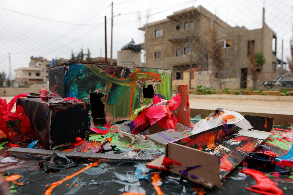 A blown up (but still used) hospital with a casket sitting to the left of the building. 