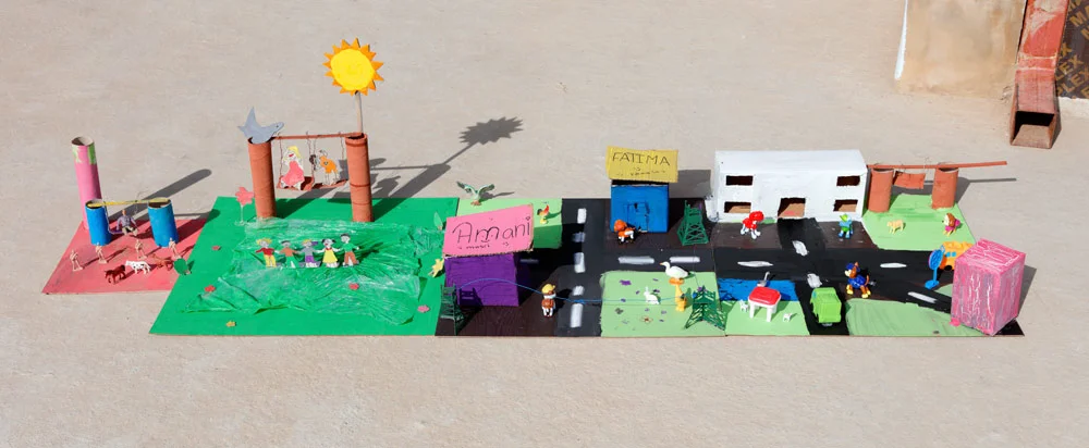 The girls designed their final, idealized city dioramas to fit together, forming one collaborative piece. The little extra playground on the end was made by a small, welcomed addition to our group. The girl's mother worked at the school, and the 6-year-old refugee quietly yet confidently staked out a spot to work on her own diorama of a "happy place” guarded by soldiers. 