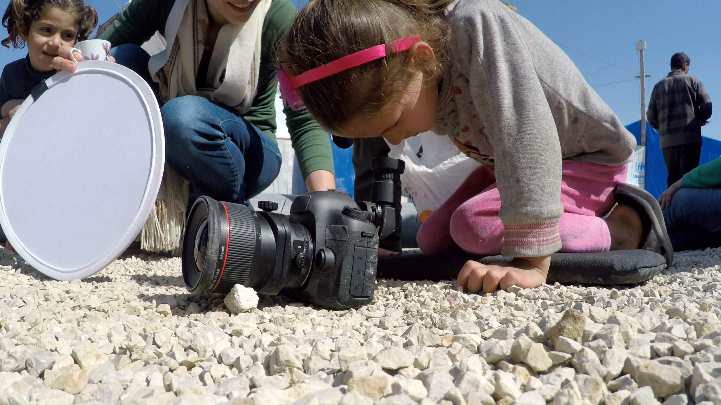 Refugee children take turns looking through the viewfinder at the toy-filled world created in front of the lens. 