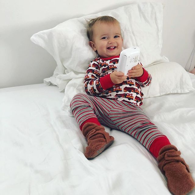 A portrait of my child in his favorite fire truck pajamas he asks for every night by making a siren sound and pointing at his chest, pushing buttons on something, lounging and playing on mama&rsquo;s bed. Oh and smiling! My love ❤️