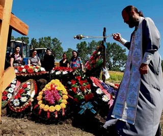 A Russian Orthodox priest blesses graves outside Krymsk.