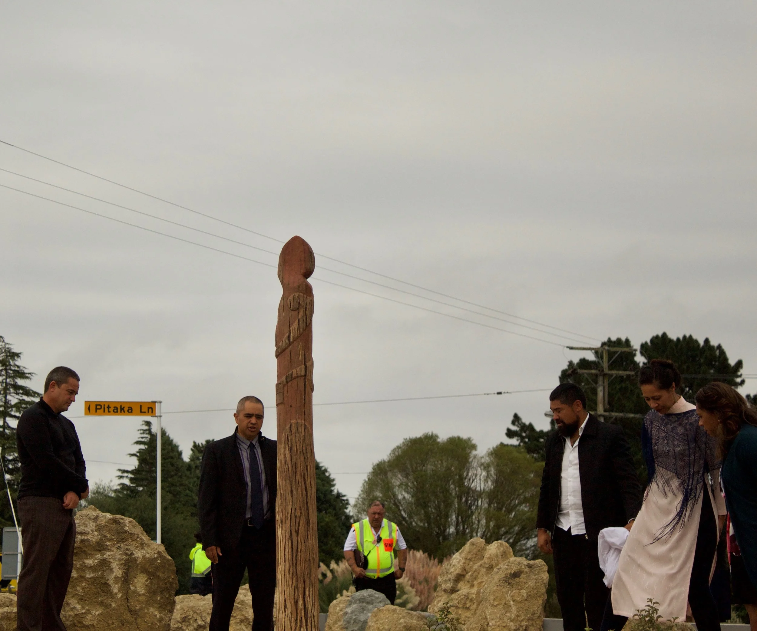 The Hawaikirangi whānau surround the Pou at the entrance of Te Piringa Papa Kāinga