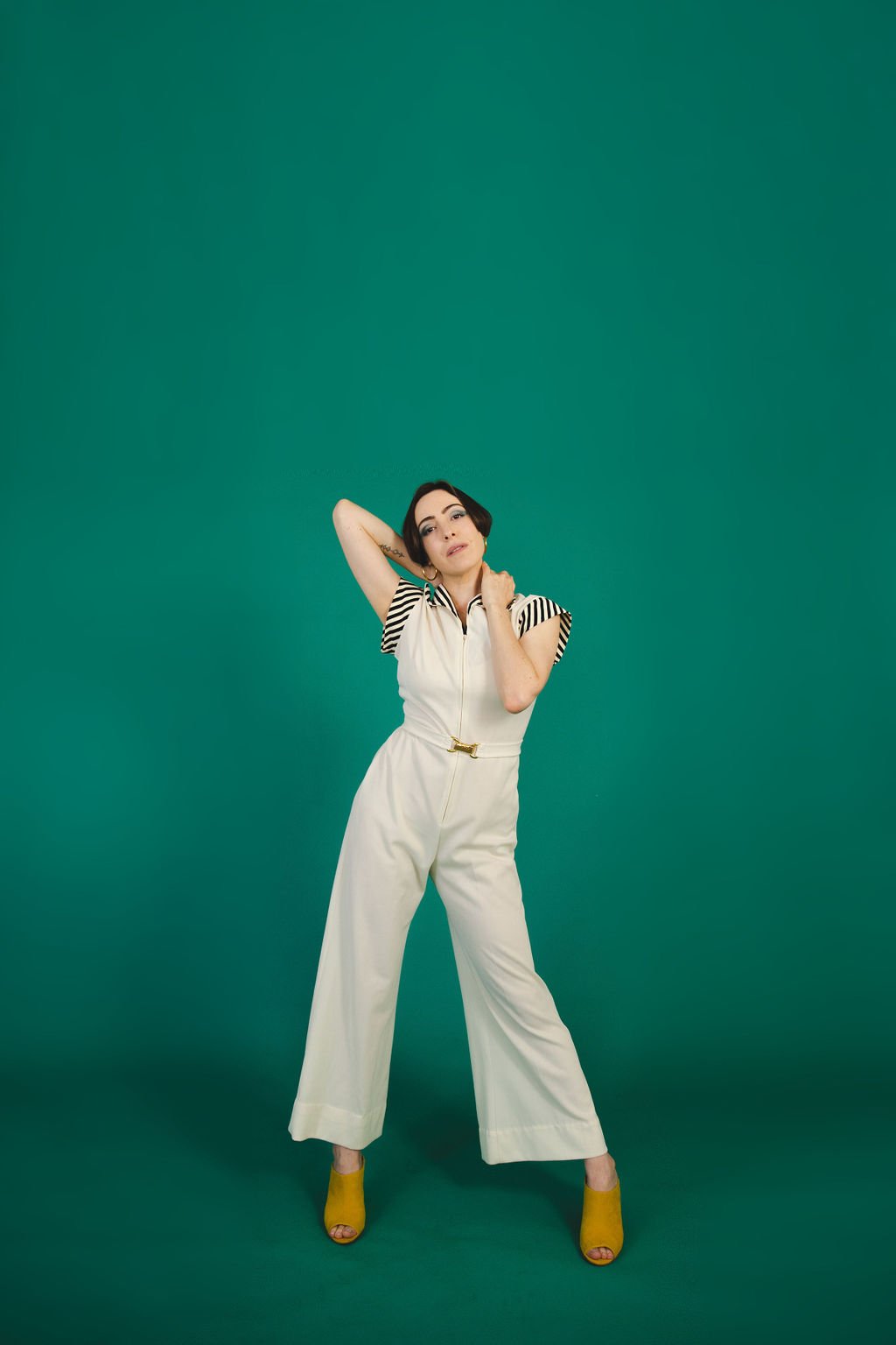  Editorial photo of actor Yvonne Cone in vintage white jumpsuit with a teal background. 