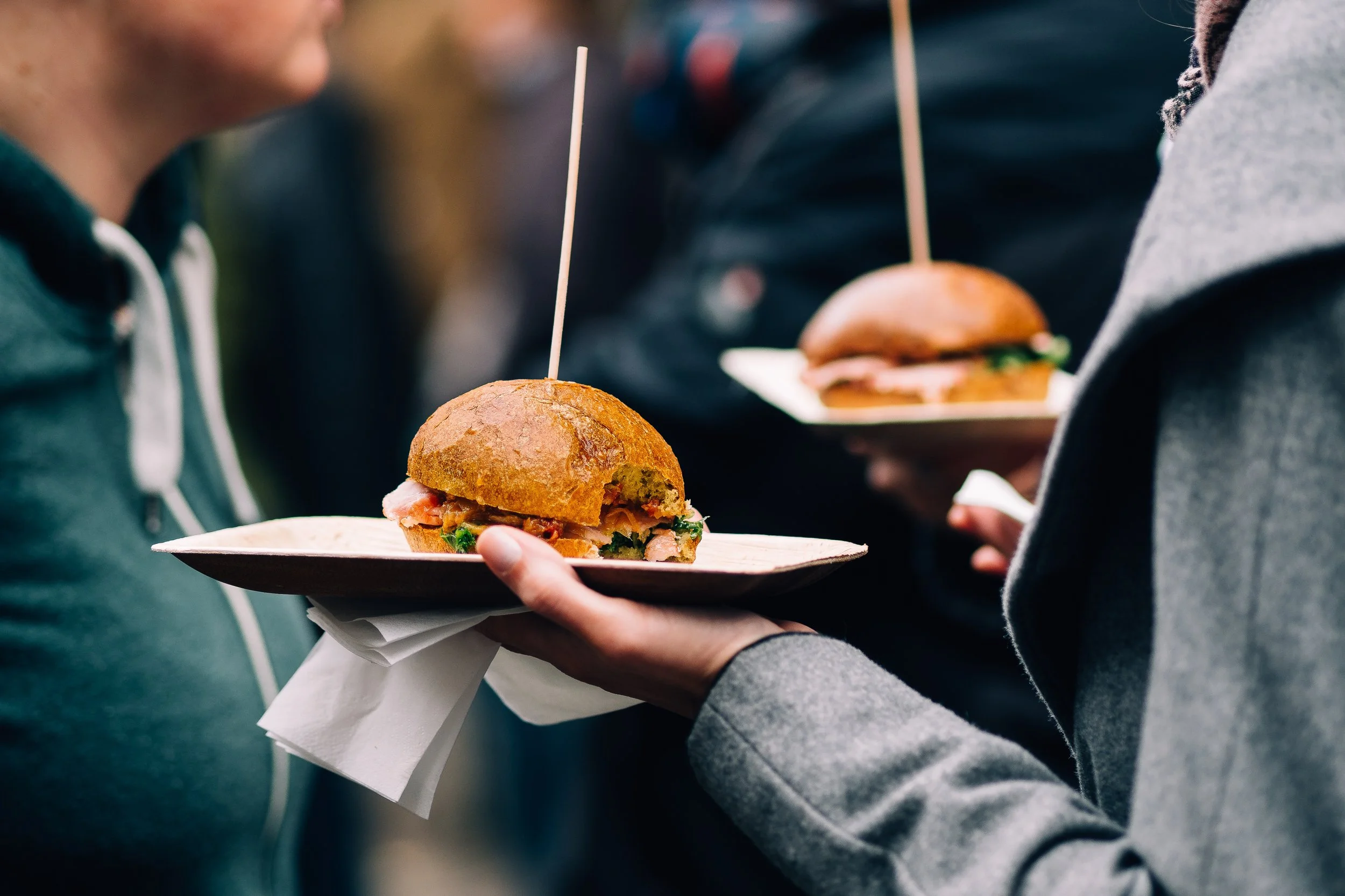 cropped-image-woman-holding-burgers-while-standing-with-friend.jpg