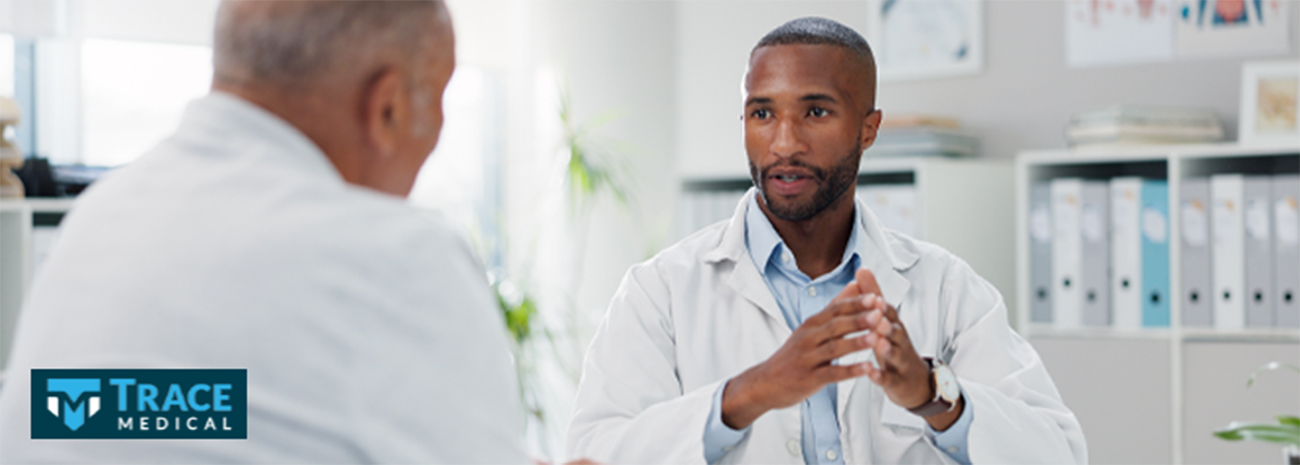 Man in a doctor's coat talking with an older man
