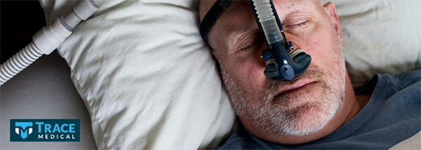 Men lying in bed with a home ventilator on