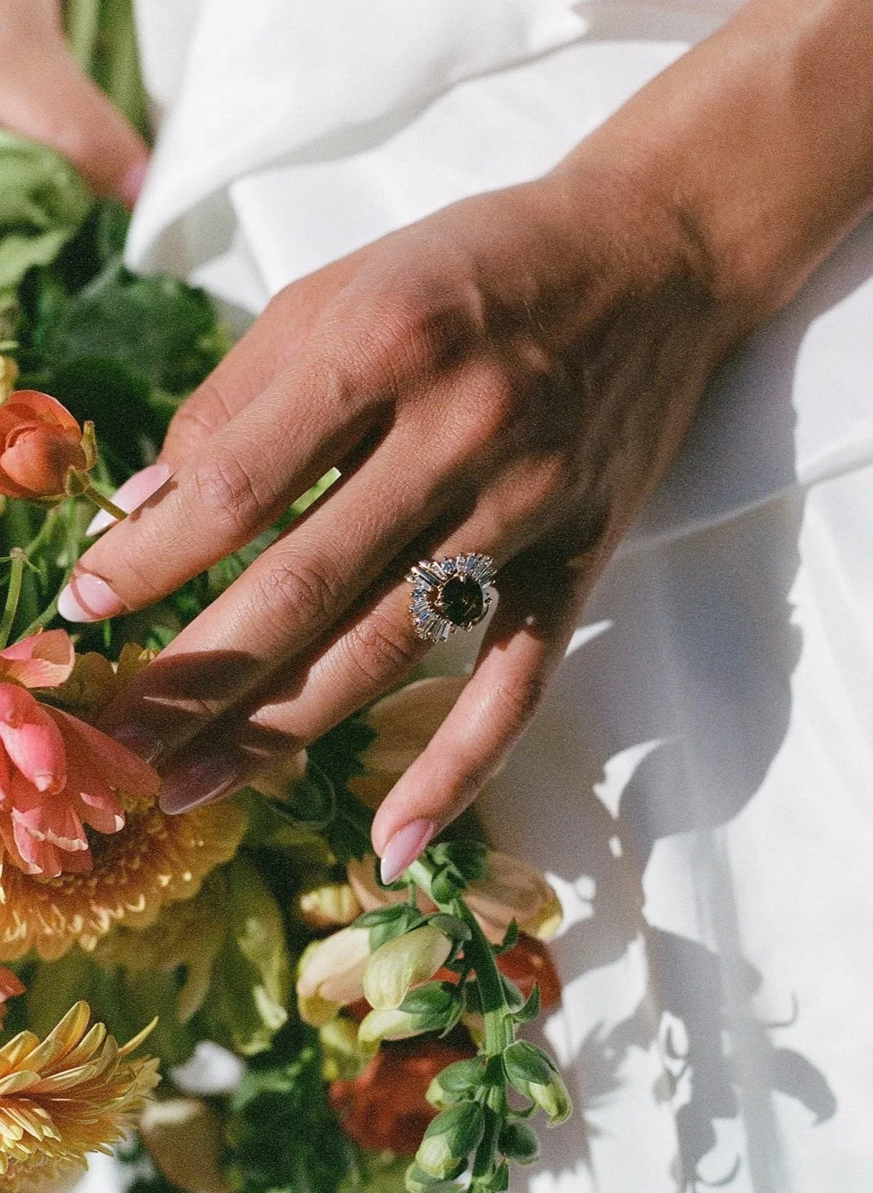 Close-up of a bride's hand with an ornate wedding set, including an east-west set cognac diamond solitaire with a baguette diamond wedding bands fanning each side.  