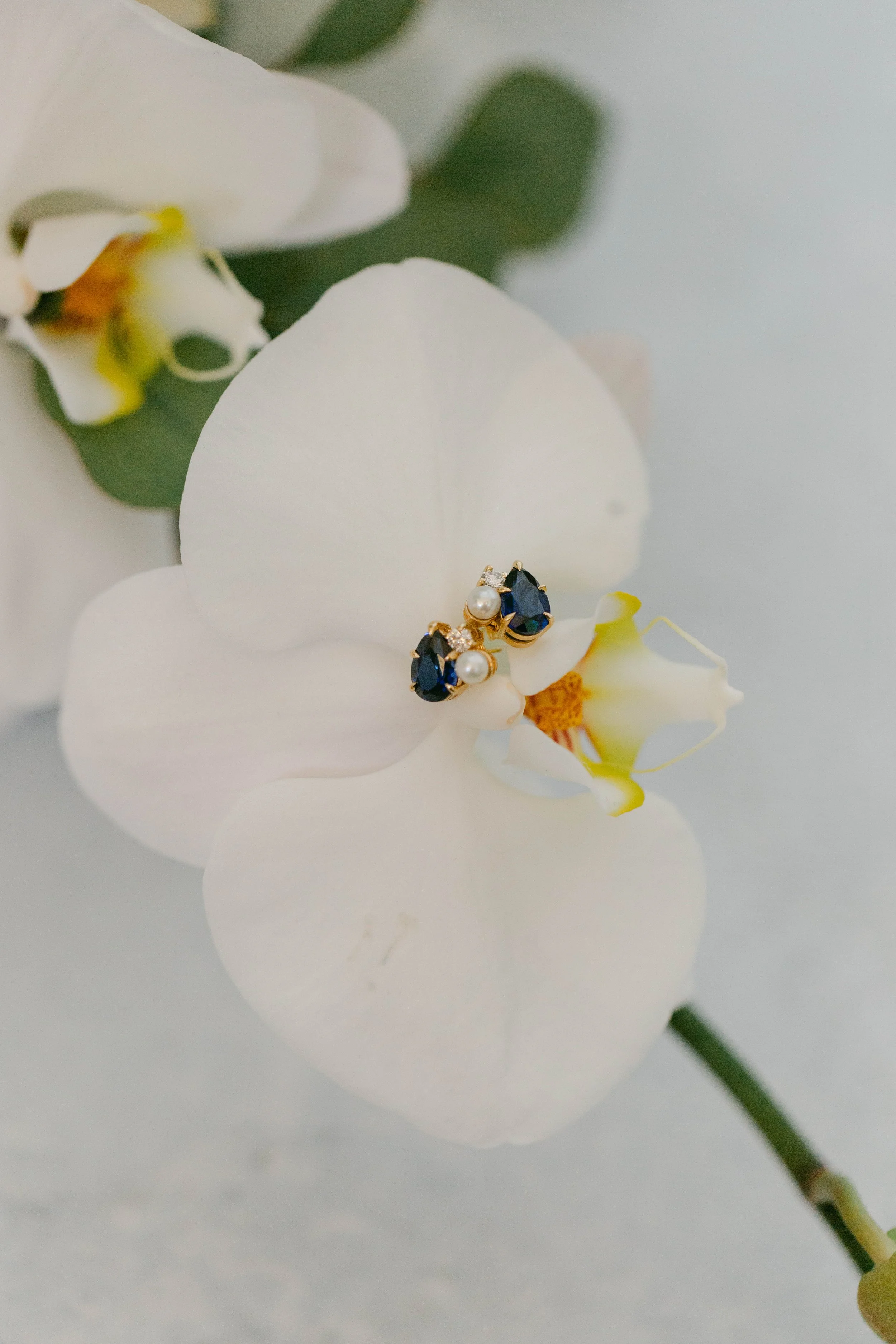 Custom designed cluster style earrings featuring a sapphire, diamond, and pearl in 14k yellow gold by Lady Cromer Jewelry.