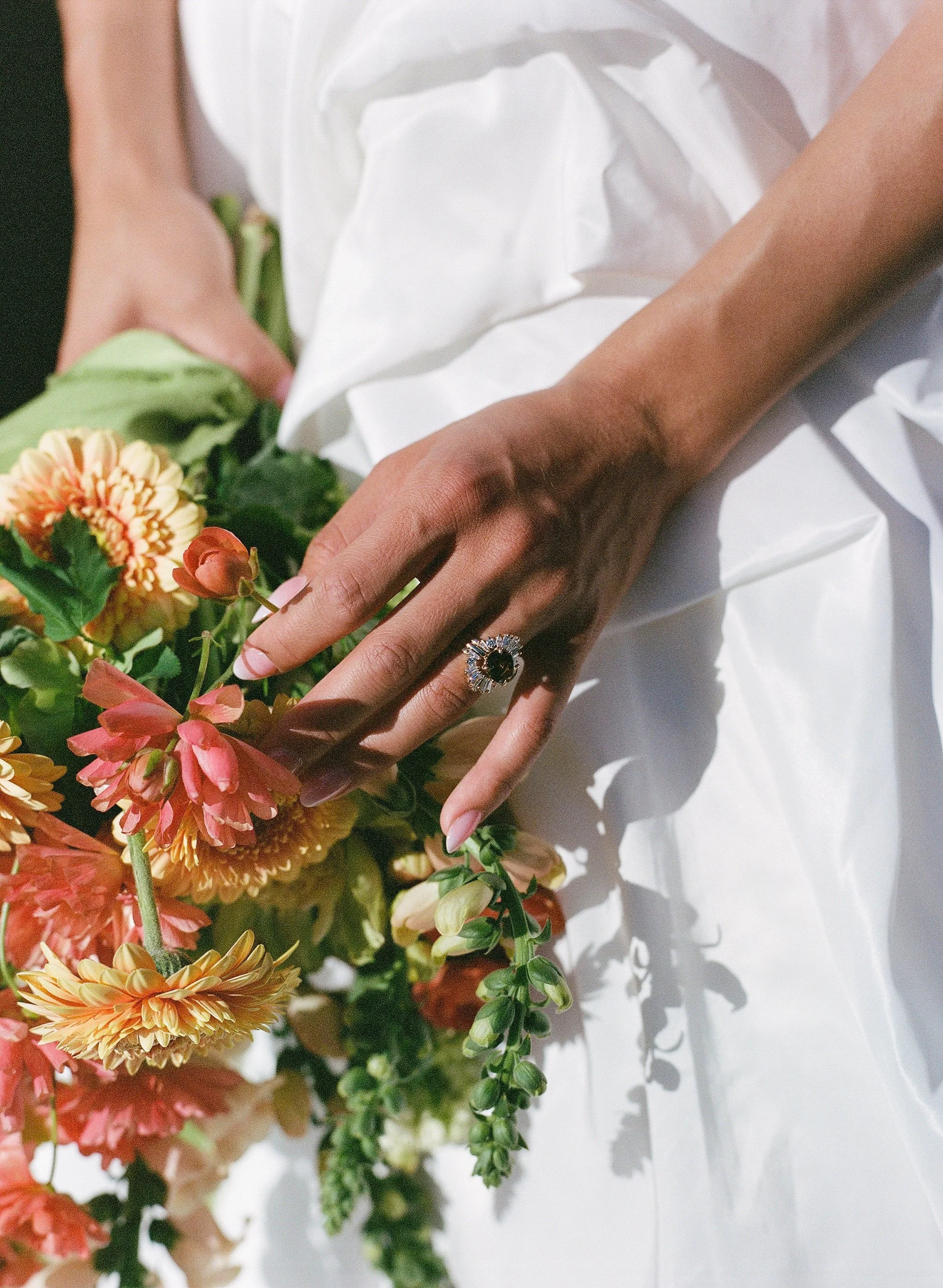 Close-up of a bride's hand with an ornate wedding set, including an east-west set cognac diamond solitaire with a baguette diamond wedding bands fanning each side.  