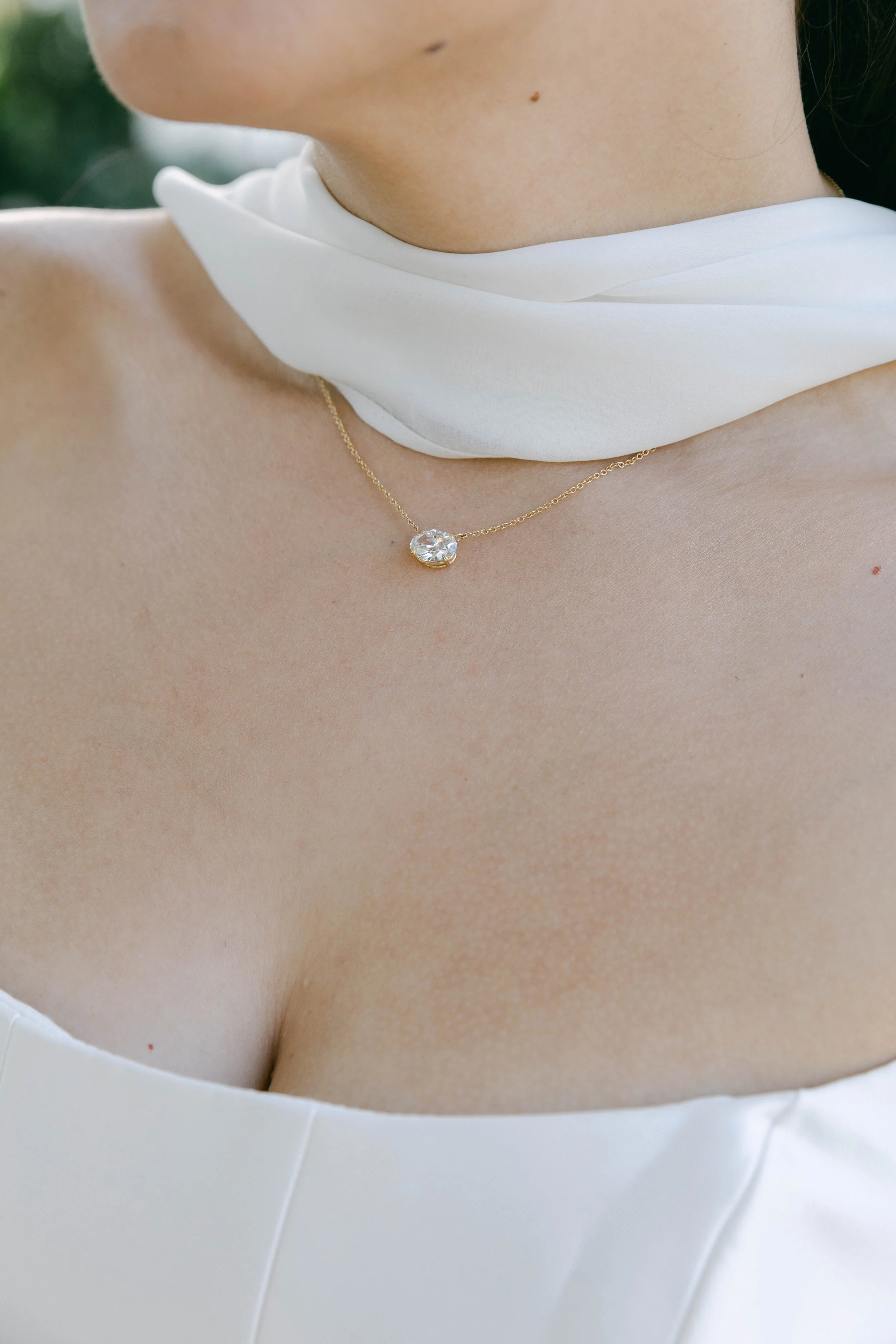 Close-up of a woman wearing a 14k gold necklace with an east-west set oval diamond. Heirloom redesign jewelry by Lady Cromer Jewelry