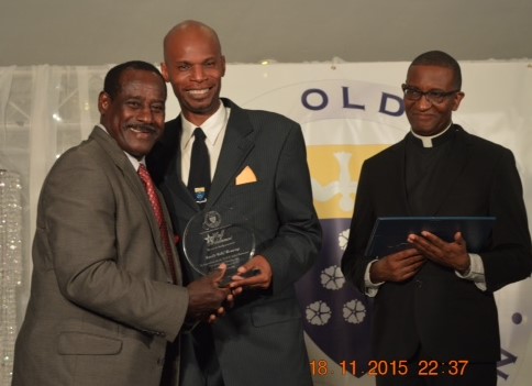 Everald “Gally” Cummings is honoured as one of the first fifty inductees into the Fatima Old Boys Association (FOBA) Hall of Achievement @ the Induction Ceremony in November 2015. Presentation made by Dwight Andrews, President of (FOBA) accompanied by Fr. Gregory Augustine, Principal of Fatima College.