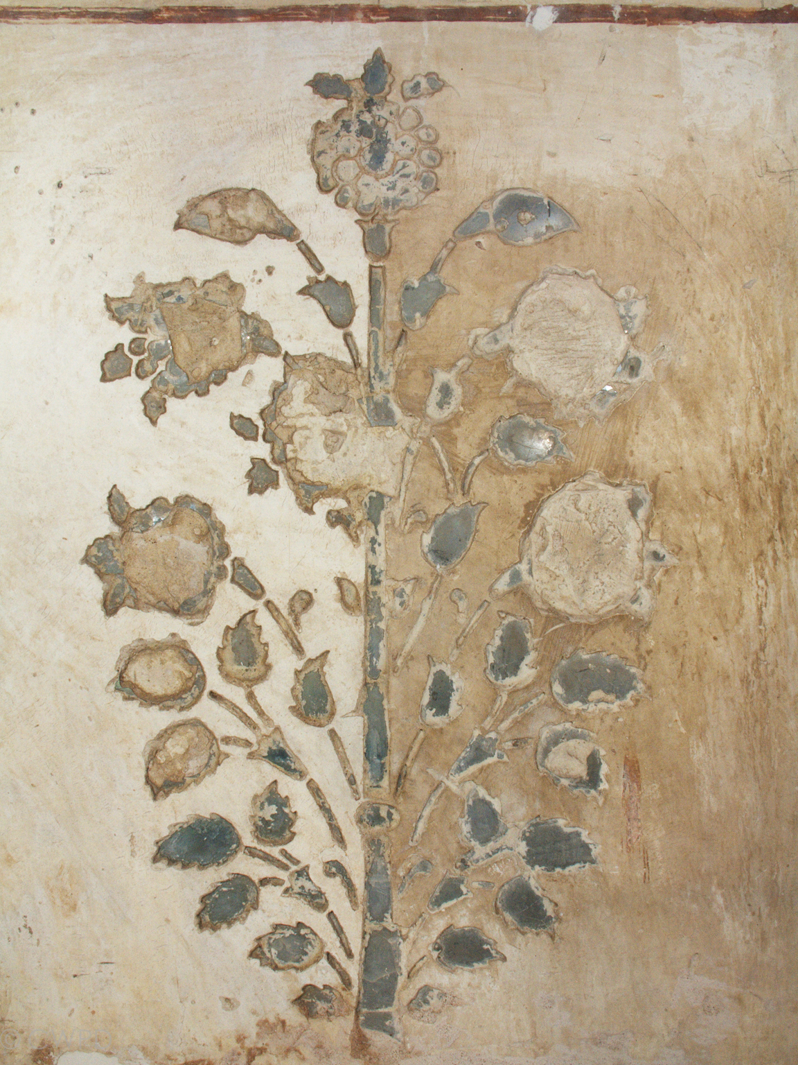  Example of the inlaid mirror work from which the palace derives its name. The image shows the  araish  during cleaning. A thick brownish-yellow dirt layer has been removed from the left side of the plaster but remains on the right side.&nbsp;  Image